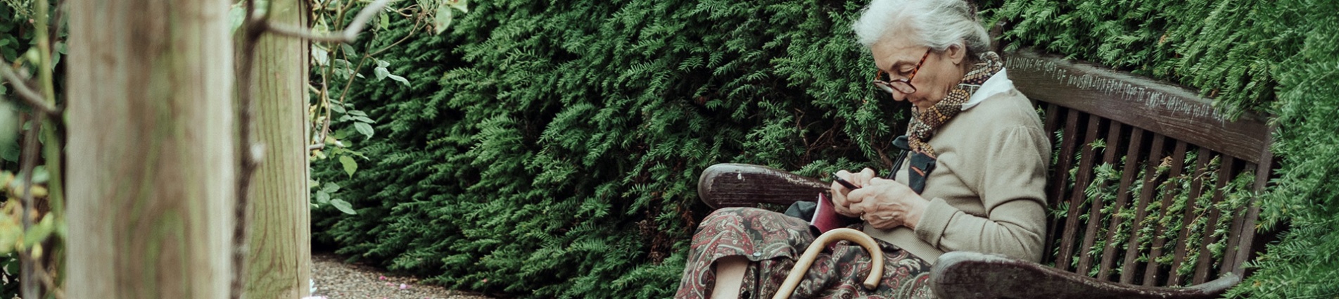 Anziana seduta su una panca in legno Anziana seduta su una panca in legno